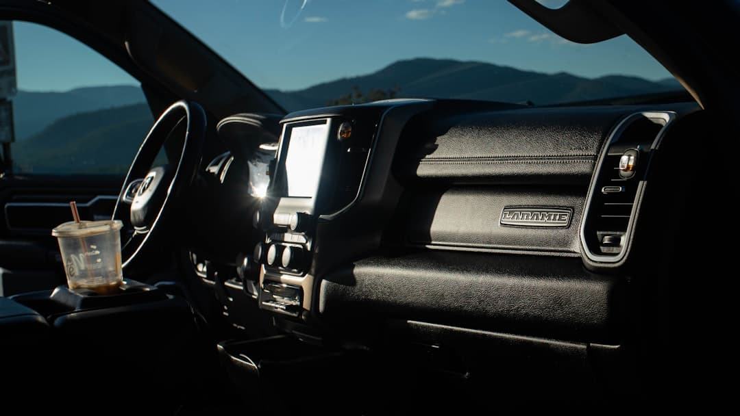 The interior of a truck with a Laramie badge and a coffee cup